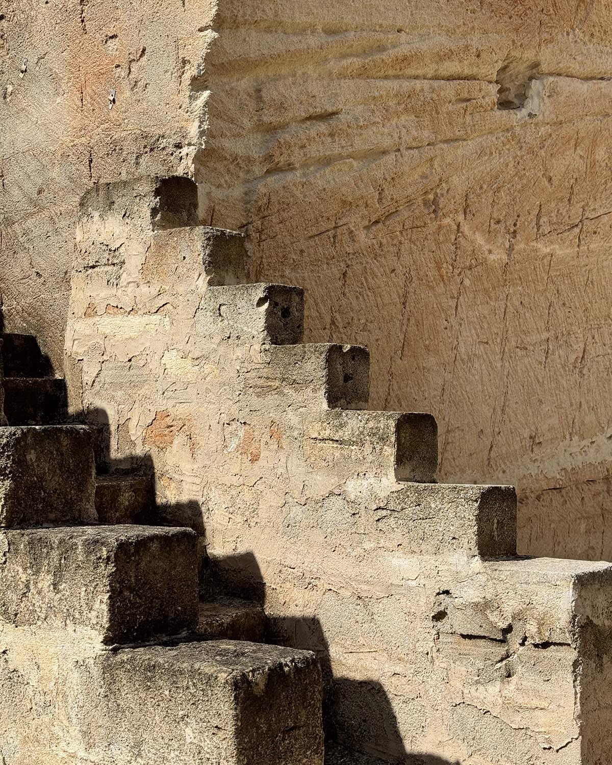 Dettaglio della cava di tufo di Mae a Favignana con scala scolpita nella pietra e superfici chiare illuminate dal sole.